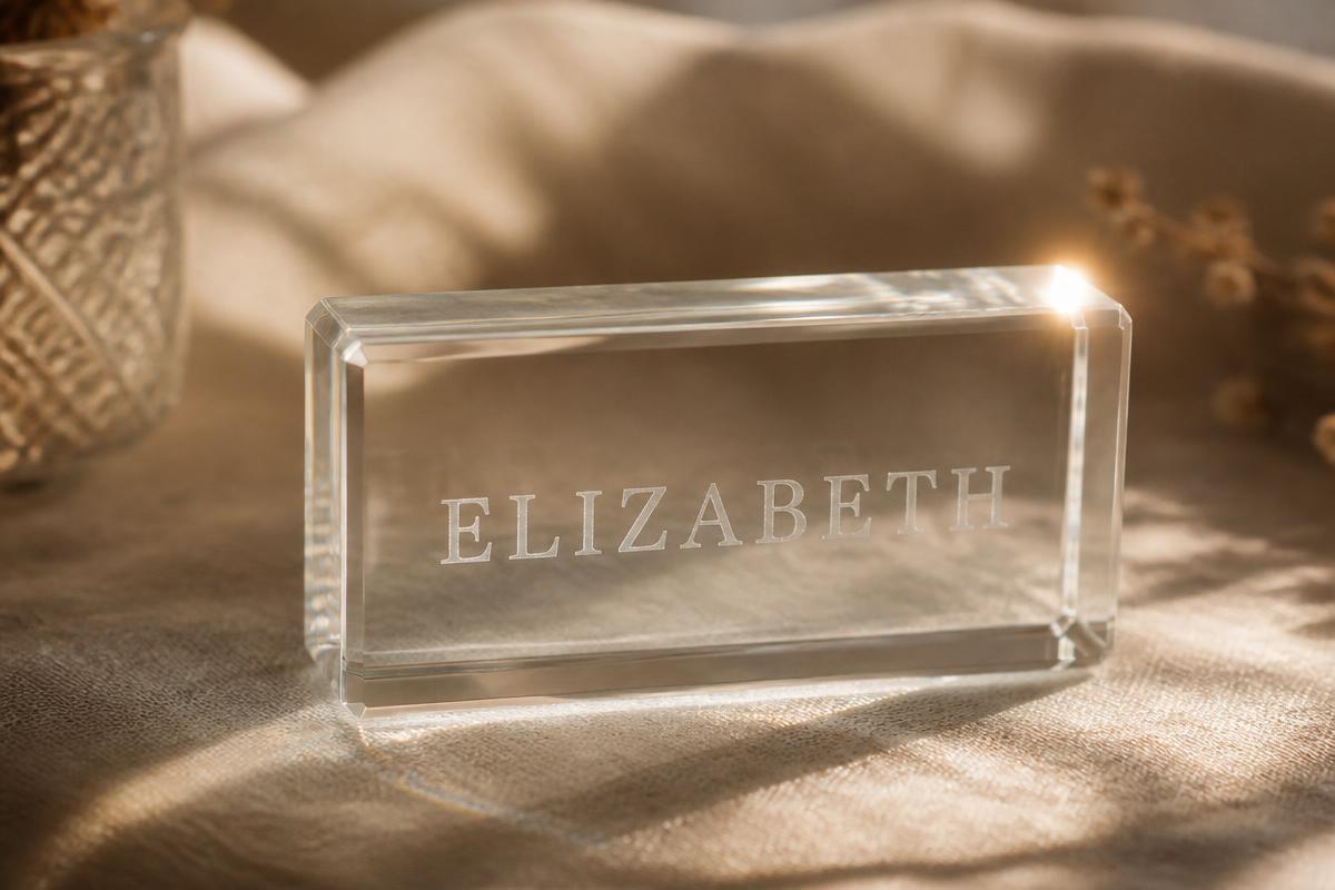 Engraved crystal block catching sunlight on warm linen